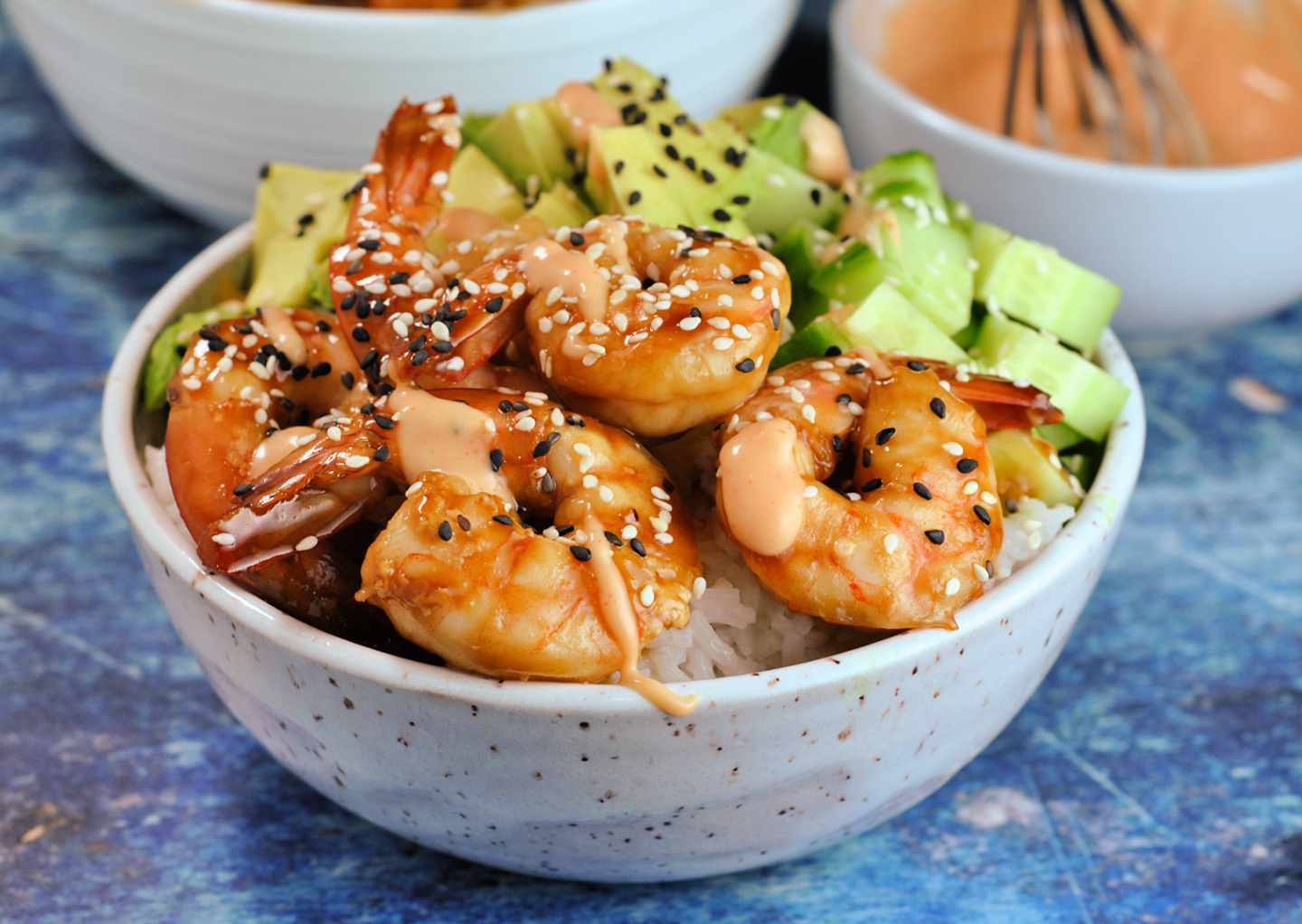 Close-up image of a shrimp rice bowl, sprinkled with black and white sesame seeds. 