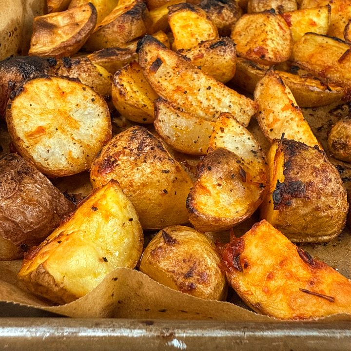 A parchment paper-lined baking sheet with crispy, harissa roased potatoes