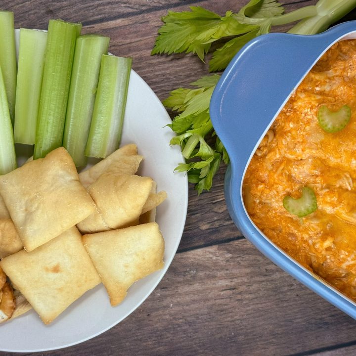 Cottage cheese buffalo chicken dip topped with melted cheddar, served with celery sticks, pita chips, and crackers.