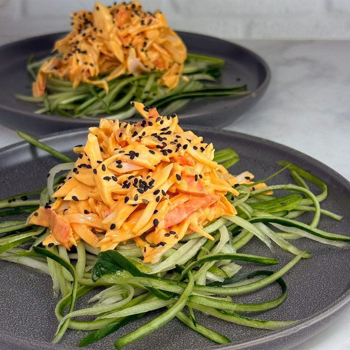 3 Ingredient Spicy Kani Salad made with shredded imitation crab in a creamy spicy mayo sauce, served over julienned cucumber noodles and topped with black sesame seeds.